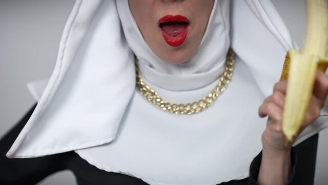 Unrecognizable smiling woman in nun costume biting banana close-up. Cheerful carefree Caucasian lady eating vitamin healthful fruit