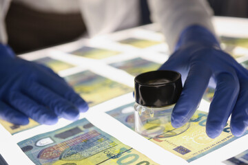 Man in rubber gloves checking authenticity of euro bills using lens closeup - obrazy, fototapety, plakaty