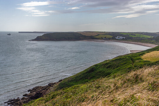 coastline between hills with village and ship on a distance