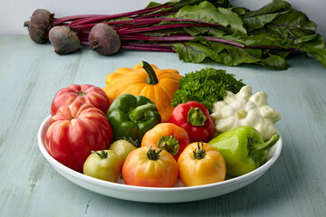 Ripe vegetables from the garden are laid out on a white plate