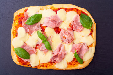 Traditional italian pizza with ham mozzarella and  basil