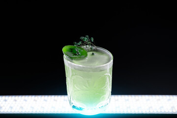 fresh green kiwi kick alcohol cocktail drink in wineglass on black background