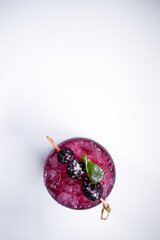 top view of alcohol blueberry special cocktail with blackberry in wineglass