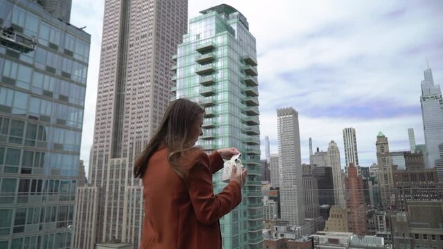 Young woman on rooftop taking picture on film instant camera at New York city.