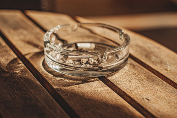 round glass ashtray in sunny natural light by the window on a table in a cafe
