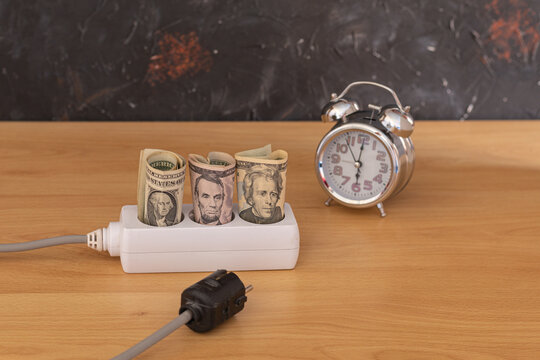 dollar money rolled up on the sockets and a clock indicating the time concept energy expenditure