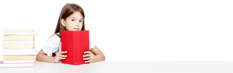 Young cute girl sitting at the table and reading a book