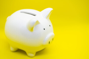 White piggy Bank on a yellow background for saving money wealth and finance concept and copy space.