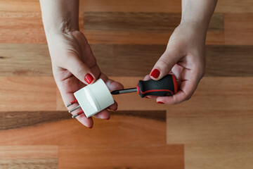 Overhead shot of a woman's hands repairing a plug using a screwdriver