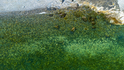 Aerial photograph of a pebble beach on the Sunshine Coast, BC. Pebbles and rocks showing through water