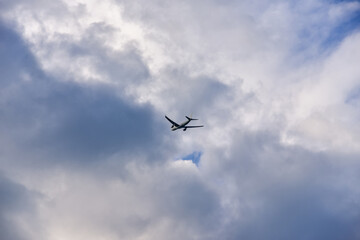 Passenger airplane is flying far away against the sky with clouds