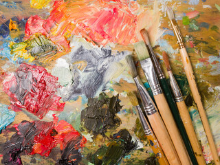 Obraz premium Artist's palette. Oil art paints extruded onto a wooden palette. Tubes and brushes lie on a colorful board