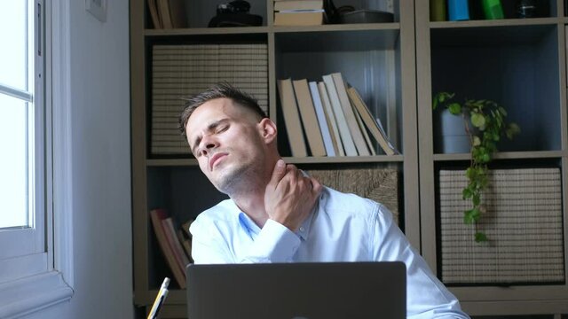 Pinched nerves, tensed sore muscles, fibromyalgia ache due sedentary lifestyle and incorrect posture concept. Caucasian ethnicity frowning man sitting at desk in front of laptop, touch neck feels pain