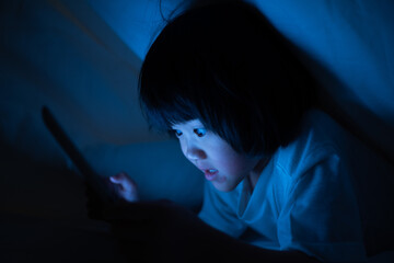 kid watching tablet on the bed, child addicted cartoon
