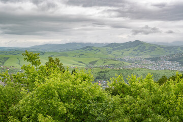 landscape with a village, a settlement in the mountains with gray stormy rainy clouds and a bunch of cottage houses