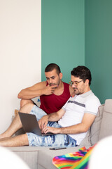 Fototapeta premium beautiful gay couple sitting on the sofa looking for something on the internet