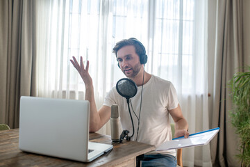 Young bearded man sitting in headphones and speaking in microphone