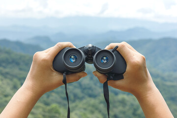 Hands holding binoculars on mountains background