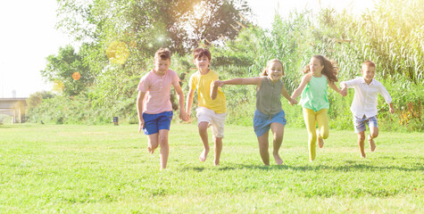 Fototapeta premium Happy active children running together on green grass in park