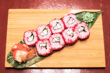 Delicious fresh rolls with red fish, cream cheese, salad leaves on a wooden plate. Sushi rolls with salmon 