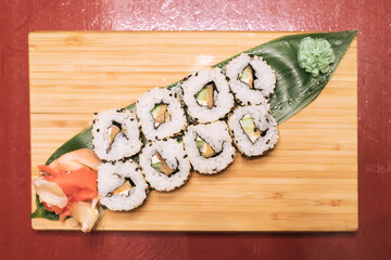 Delicious fresh rolls with red fish, awakad, cream cheese, lettuce, sesame seeds, on a wooden worthy. Salmon sushi rolls 
