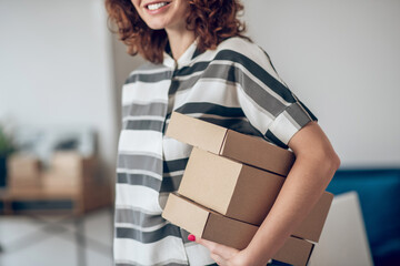 Smiling joyous female worker with packages standing insid