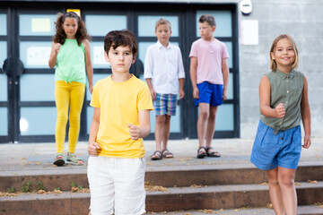 Smiling preteen schoolchildren boy and girl walking home after finishing lessons on summer day