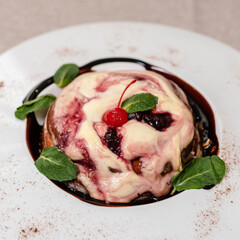 Dessert of cottage cheese with cherries and mint on a white, ceramic plate 