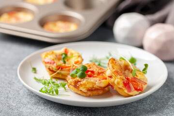 Egg muffins  or bites with vegetables and micro greens  in a plate on a gray background
