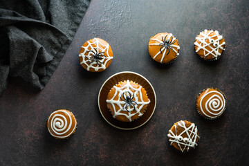 Top down view of various cupcakes decorated for Halloween, scattered about against a dark background.