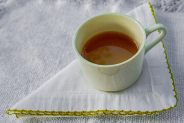 Cup of tea over a white handkerchief. Beautiful cup composition. Background.
