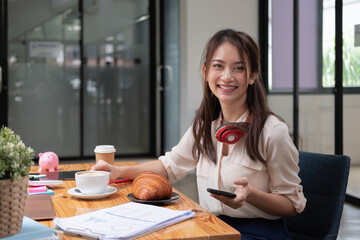 Beautiful young Asian girl working at a office space with a mobile phone. Concept of smart female business accounting