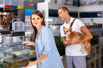 Fototapeta na wymiar friendly woman and boy with interest looking at small aquarium in pet shop