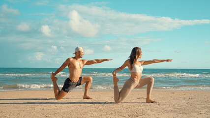 Couple training - Young sports couple doing acro yoga exercises on sand beach. Couple making yoga exercises on sand. fitness, sport, people and lifestyle concept, Caucasian fitness model.