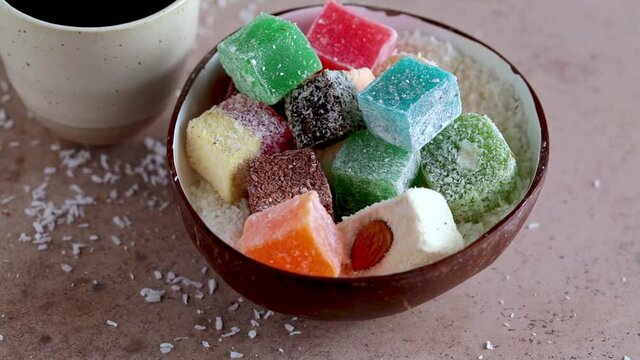Turkish delight of different types in coconut bowl, dark background.