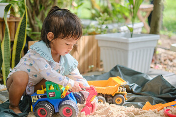 Cute Asian young toddler girl playing with sand alone at home, Kid playing with sand toys & toy...