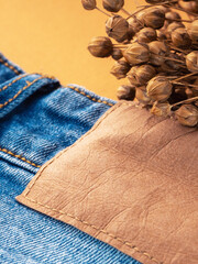 Blue jeans with a brown leather blank label and dry linen, close-up. Jeans texture. Fashion denim background for sewing, copy space. Label on clothing to indicate the size, company