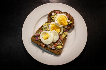 Avocado toast with egg, bacon bits and onion