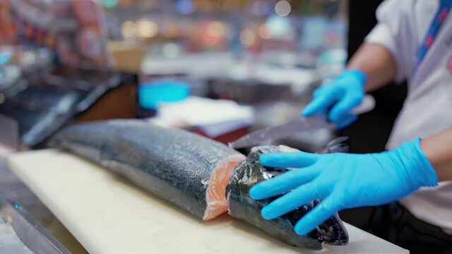Close up to Hand of professional asian checf or fishermen preparing fresh salmon fish by slice and cutting at fish market 