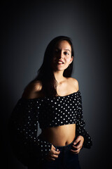 Close-up portrait of a young woman with a positive gaze looking at the camera, on a dark studio background