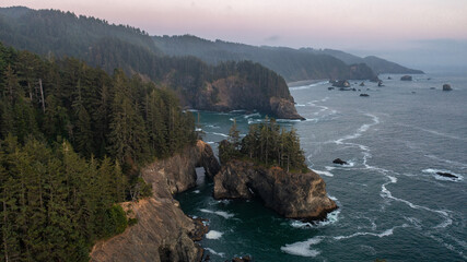 Aerial view of the coast of Oregon during sunset. The ocean can be seen with an arch at the Samuel...