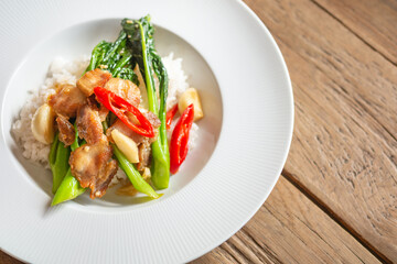 Thai food Crispy pork stir fry with chinese kale topped on stream rice in white dish