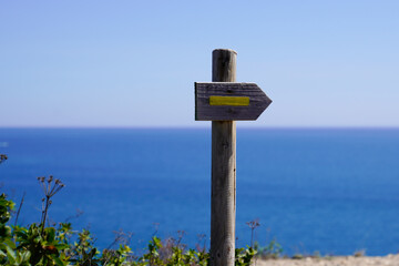 wooden yellow arrow pointing the direction of footpath for hike trail in ocean sea coast walk