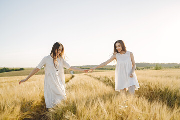 Portrait of two sisters in white dresses with long hair in a field