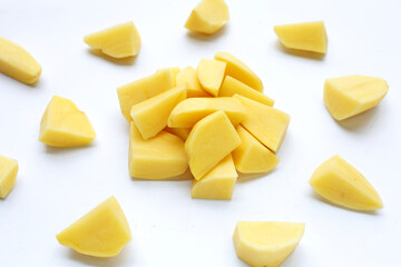 Raw potato cut into pieces on white background.