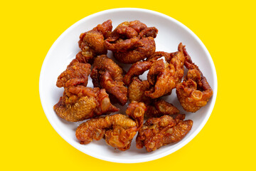 Chispy fried chicken skin in white bowl on yellow background.