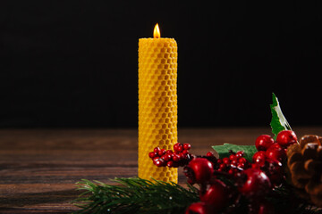 A yellow foundation candle stands on the table with a spruce twig. Ecological product made from...