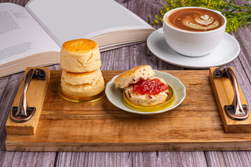 Scones traditional English delicious freshly baked homemade with strawberry jam and served on a wooden tray with a coffee cup. Top view. Dessert, beverage, and relaxation concept