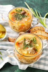 Bowls with tasty beef barley soup on color background