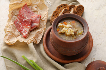 Pot with tasty beef barley soup on grunge background